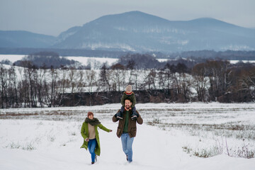 Obraz premium Father, mother and young son on walk in winter nature.