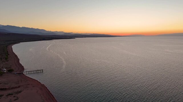 Stunning drone view of Issyk-Kul Lake at sunset, showcasing golden skies