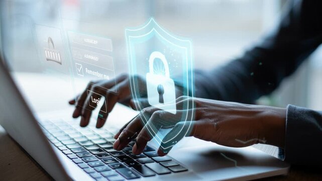 Close up of hands typing on a laptop with a translucent login screen and glowing shield icon featuring a lock as keystrokes trigger light particles signaling secure data transfer