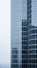 Obraz premium Modern glass skyscraper on foggy day in urban cityscape
