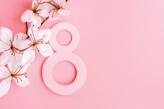 Postcard March 8. Greeting card women s day. Paper number eight decorated with white flowers on a pink background