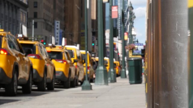 Manhattan Midtown street New York City, United States. Defocused row of yellow taxi cars. Many taxi cabs in line on 8th avenue near Penn Station. Taxi queue, urban road traffic, passenger transport.