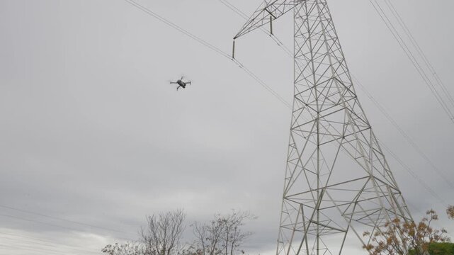 An engineer inspecting high voltage power lines with a drone