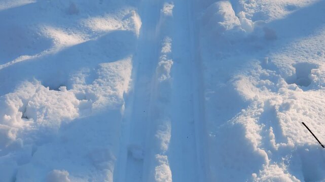 Fresh ski tracks cut through pristine white snow. Sunlight casts long shadows across the parallel grooves. A perfect winter scene for outdoor sports and recreation.