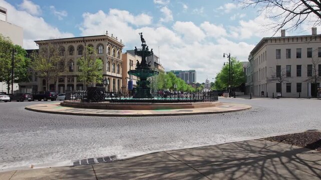 Large circular water fountain waterfalls in the center of a street roundabout car road with traffic at downtown travel destination and capital city in deep south United States of Montgomery, Alabama