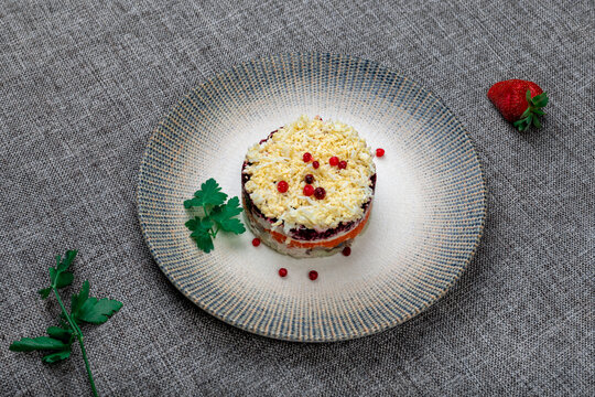 Traditional Russian layered "dressed herring" salad ("Selyodka Pod Shuboy") on a rustic plate.