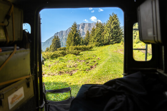 Pararul Recce, Romania - 07 June 2025: View of verdant hills and towering evergreens framed by the rugged interior of a vehicle, a portal to the serene landscape.