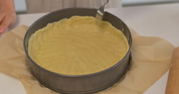 Close-up of making holes with fork in shortbread dough inside springform pan