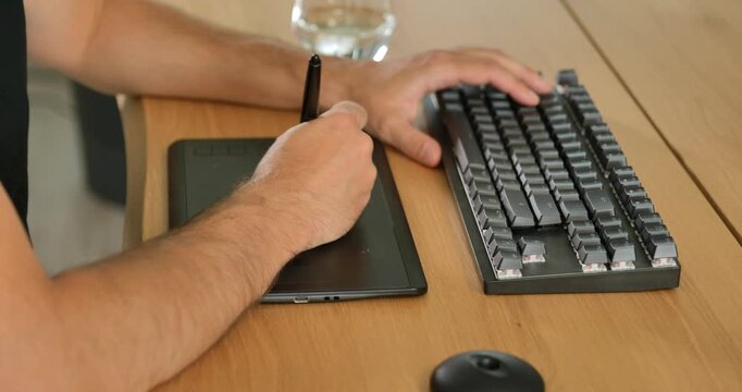 Creative professional using keyboard and graphic tablet at desk.