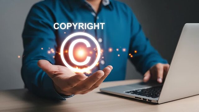 Person holding glowing copyright symbol with laptop in background intellectual property protection concept