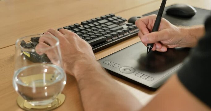 Creative professional using keyboard and graphic tablet at desk.
