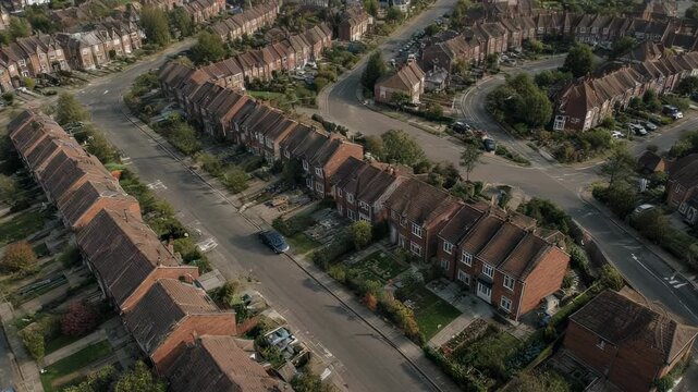 Aerial shot of suburban street with red brick houses, cars, and green vegetation