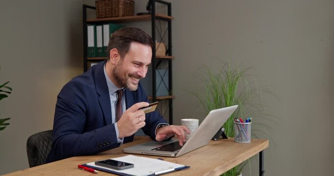 Businessman paying online with credit card at office desk