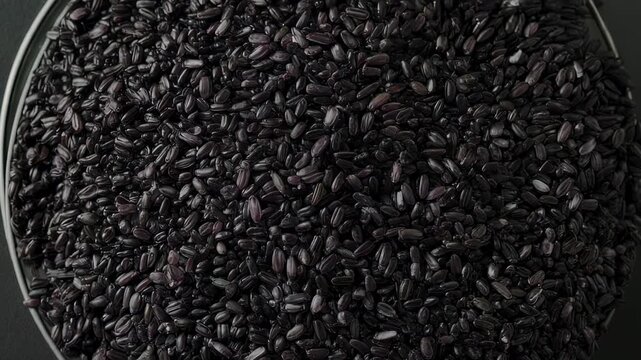 Overhead shot of a bowl filled with black rice. The shiny grains fill the frame