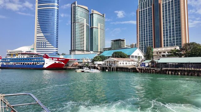 Dar Es Salaam, Tanzania: Tilt up footage of waterfront area in Dar Es Salaam downtown, capital city of Tanzania with boats docked and skyline in the background under blue sky
