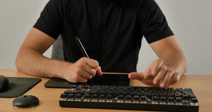 Creative professional using keyboard and graphic tablet at desk.
