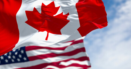 Obraz premium Canada and american national flags waving in the wind on a clear day