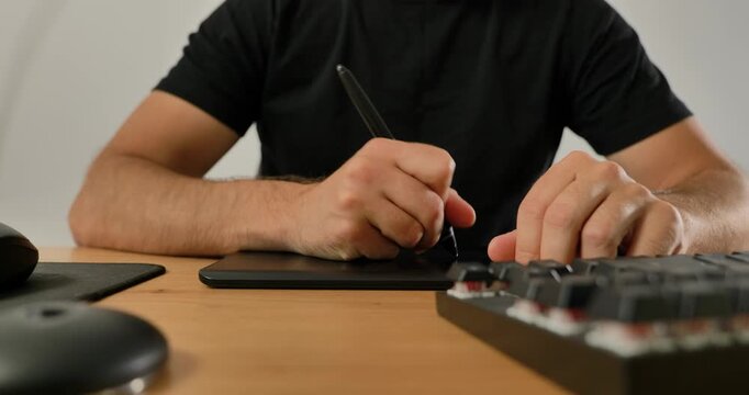 Creative professional using keyboard and graphic tablet at desk.