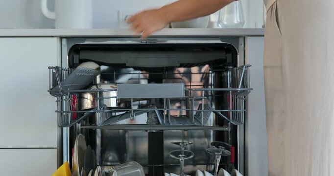 Woman loading dishes into dishwasher in modern kitchen