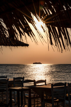 Beautiful sunset at the Aegean sea, Samothrace or Samothraki island Greece, tree and ship or boat silhouette, enjoying summer vacation, wellness and tourism, restaurant on the beach