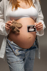A pregnant woman holds an ultrasound image of her baby on her rounded belly. A tender and touching moment of anticipation