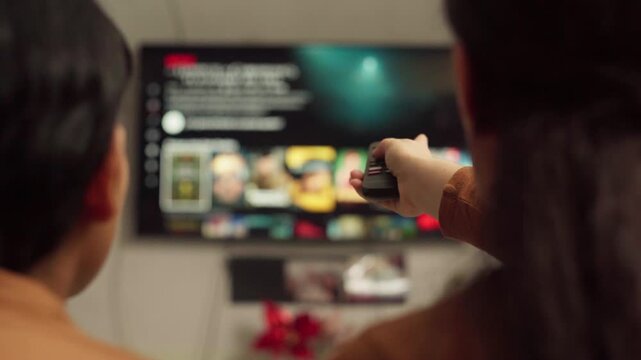 Couple choosing a movie with a remote control while browsing a streaming service on smart television at home