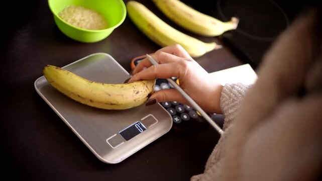 Nutritionist Weighing Banana On Electronic Kitchen Scale. Counting Calories With Smartphone Calculator. Healthy Diet Planning