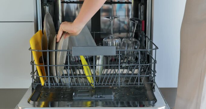 Woman loading dishes into dishwasher in modern kitchen
