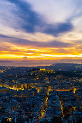 Obraz premium Panorama of Athens at sunset with a view of the Acropolis. The city lit up at night against the backdrop of enchanting clouds and a mesmerizing sunset. A peaceful picture of relaxation 