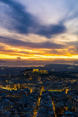 Fototapeta premium Panorama of Athens at sunset with a view of the Acropolis. The city lit up at night against the backdrop of enchanting clouds and a mesmerizing sunset. A peaceful picture of relaxation 