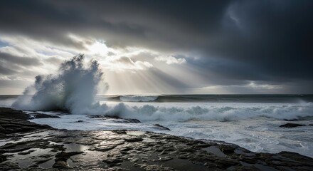 Obraz premium Dramatic ocean wave crashes against rocky shore under stormy, sunlit sky