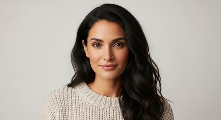 Obraz premium A woman with long, dark hair wearing a white knitted sweater and looking directly at the camera