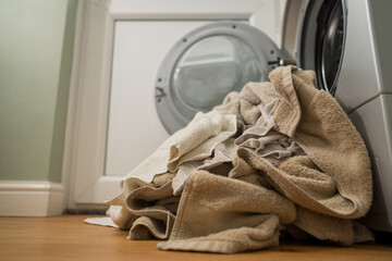 Washing machine with dirty towels on the floor near it. Laundry washer with opened door. Lifestyle. Copy space