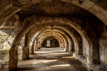 Fototapeta premium Ancient stone arches in the underground tunnels of the Agora of Smyrna in Izmir, Turkey. Historical archaeological site with antique architecture and old stones on a sunny day .