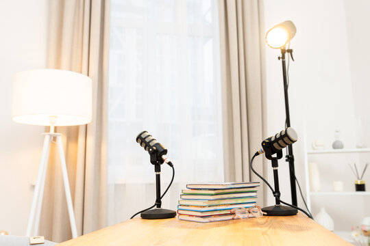 Discussion on education takes place at home with two microphones and books stacked on the table during a podcast recording