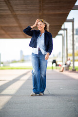 Fototapeta premium Happy mature woman walking confidently outdoors in casual jeans