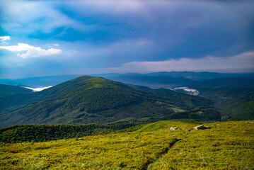 Obraz premium Scenic view of hills and valleys under a cloudy sky in a mountainous region during daytime