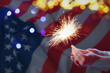 American flag and woman holding burning sparkler, double exposure. National holiday celebration