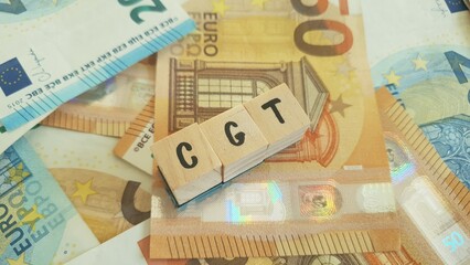 CGT acronym made of wooden letter cubes on pile of Euro banknotes. Capital Gains Tax