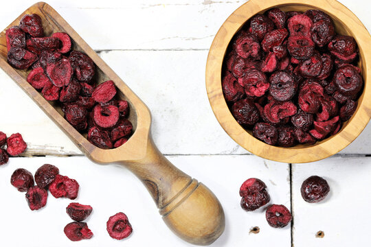 freeze-dried sour cherries in olive wood tableware on rustic wooden background