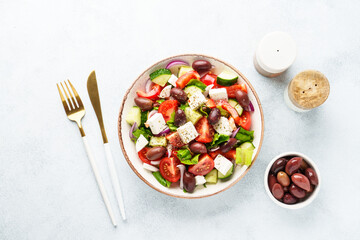 Greek salad in craft plate on white kitchen table.