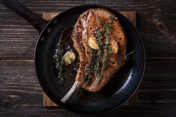 Pan-fried pork loin in a cast iron skillet on a wooden table. Top view.