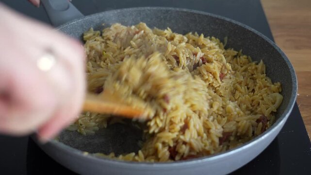 Cooking orzo pasta in frying pan on induction cooker