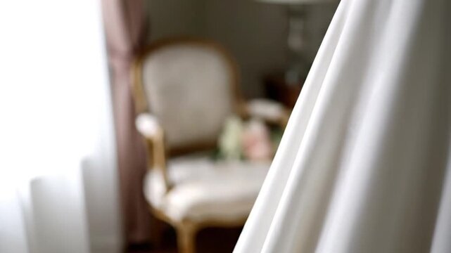 White wedding dress fabric with elegant folds and a blurry classic chair in the background, bridal preparation concept