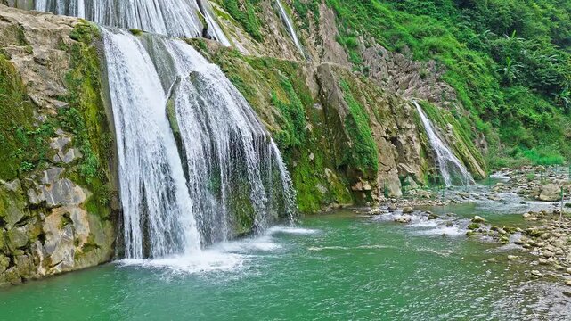 Aerial view of the beautiful waterfall cascading over rocky cliffs into a river in Guizhou, China. 