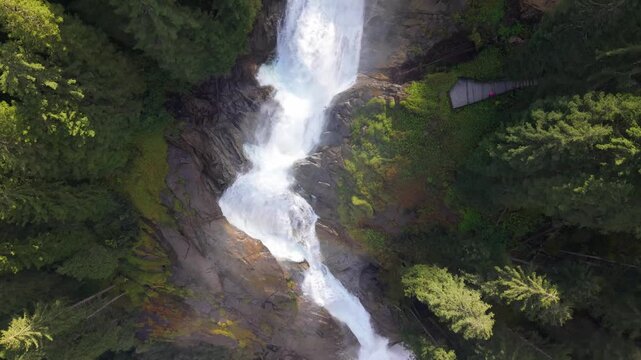 View from above of water flowing down the mountain among the trees. Aerial footage of the Krimml Waterfall in the middle of the forest, Austrian Alpine natural landscape