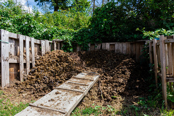 An image of fenced in pile of horse manure composting in the sunlight and to be later used as organic garden fertilizer. 