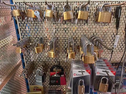 Pamplona, ​​Spain - January 31, 2026. A hardware store display with a wide variety of security padlocks, mainly brass and steel, hanging on a perforated metal panel. Keyed and combination padlocks .