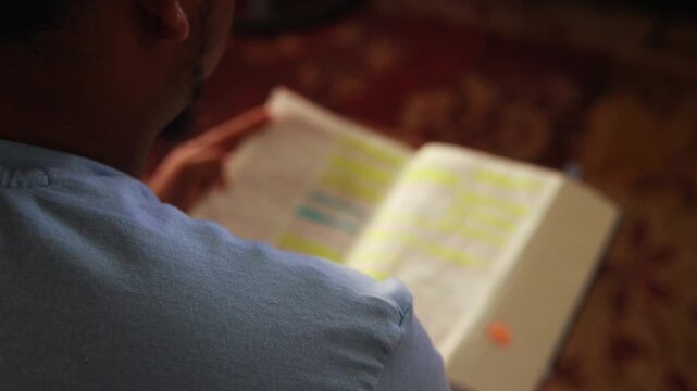 Young male student reading and studying a highlighted book