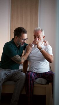 Son supporting father after surgery, helping him to recover.